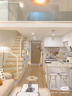 a living room and kitchen with stairs leading up to the top floor in an apartment