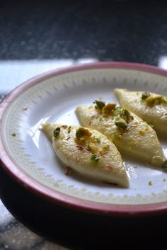 three pieces of food on a white and pink plate sitting on a black table top