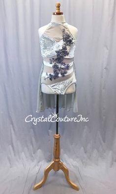 a dress on a mannequin stand with white and blue flowers in the back