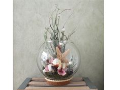 a glass vase filled with flowers and seashells