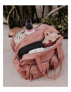 an open pink purse sitting on the ground