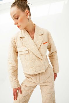 Colour: beige with contrasting threads Fabric: Main fabric is 100% vegan silk, lining is 100% cotton Opening system: hidden snaps Details: beige with contrasting thread stitches, quilted vegan silk, notched lapels, front hidden snap fastening, long sleeves, straight hem, cropped, apple leather imitation handkerchief pocket and flap pockets. Beige Quilted Outerwear For Work, Quilted Beige Cotton Outerwear, Beige Quilted Cotton Outerwear, Cream Outerwear With Padded Collar For Work, Cream Outerwear With Lapel Collar And Patch Pockets, Quilted Beige Outerwear For Spring, Quilted Beige Spring Outerwear, Beige Cotton Blazer With Suit Collar, Beige Long Sleeve Quilted Jacket With Pockets