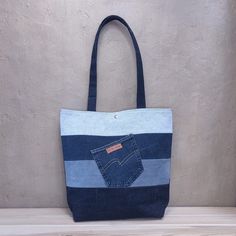 a blue and white striped tote bag sitting on top of a wooden table next to a wall