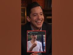 a man is smiling and holding up a card with an image of himself on it