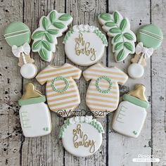 baby shower cookies decorated with green and white icing on a wooden table next to other decorations