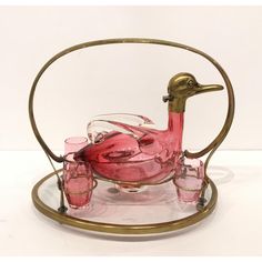 a pink glass duck sitting on top of a table next to glasses and a tray