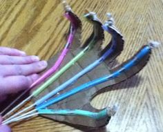 a person is holding scissors in their hand on a wooden table with several different colored wires attached to it