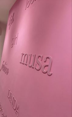 a pink wall with the word museum written in silver on it's side, along with other words