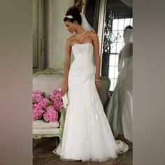 a woman in a white wedding dress standing next to a chair with pink flowers on it