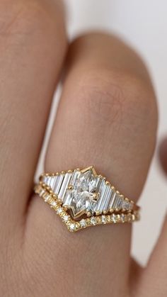 a woman's hand with a diamond ring on top of her finger and an engagement band