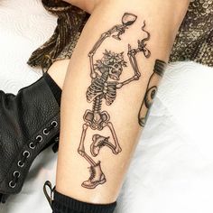 a woman's leg with a skeleton and wine glass tattoo on her left arm