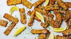 lemon and parmesan bread sticks are arranged on a white surface with sliced lemons