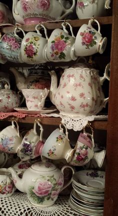 there are many teapots and cups on the shelves in this store, all decorated with pink flowers