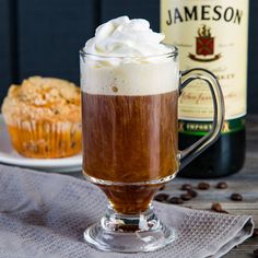 there is a cupcake with whipped cream on top and a bottle of jameson in the background