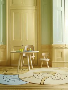 a table and chairs in a room with green walls on either side of the door