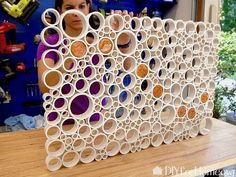 a woman is looking at an art piece made out of plastic tubes and other items