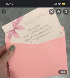 a person holding up a pink envelope with a bow on the front and back side