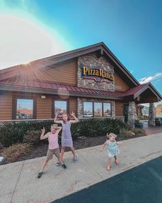 two children are jumping in front of a pizza ranch restaurant with the sun shining on them