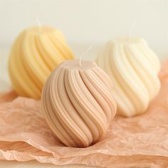 three different colored candles sitting on top of a piece of wax paper next to each other