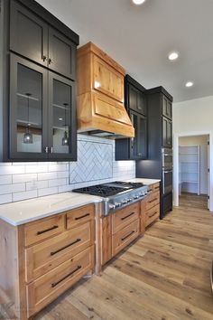 a kitchen with black cabinets and white counter tops, wood flooring and hardwood floors