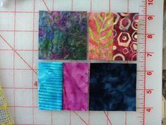 four square pieces of fabric laid out on a ruler