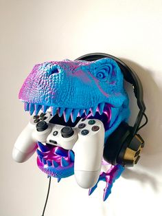 two video game controllers are hooked up to a wall mounted dinosaur head with large teeth