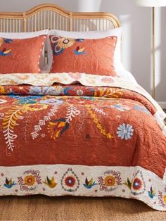 a bed with an orange comforter and two pillows