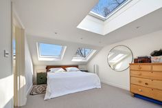 a bedroom with skylights and a bed in the corner next to a chest of drawers