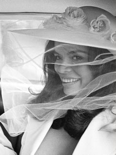 a woman in a car wearing a hat with flowers on it's brim