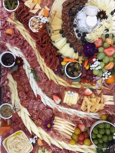 an assortment of meats and cheeses arranged on a platter with olives