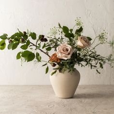 a white vase filled with flowers on top of a table