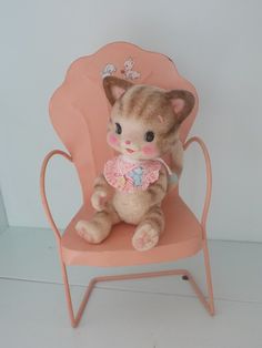 a stuffed cat sitting on top of a pink chair