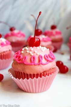 cupcakes decorated with pink frosting and cherries