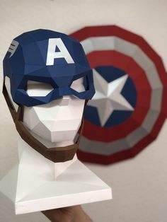 a captain america paper mask on display in front of a red, white and blue wall