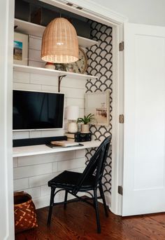 a room with a chair, desk and computer monitor on top of a shelf next to a door