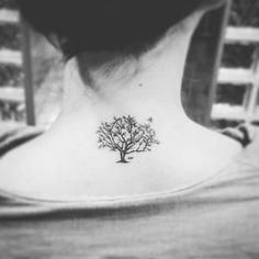 a woman's back neck with a small tree tattoo on the left side of her neck