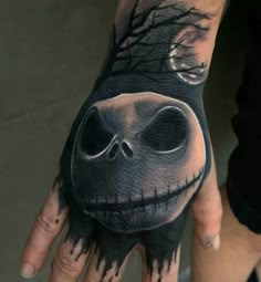 a person's hand with a black and white tattoo design on it that has a creepy face in the middle