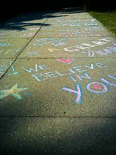 chalk writing on the sidewalk in front of a house