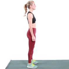 a woman standing on a yoga mat with her hands behind her back