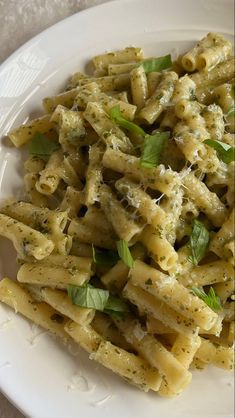 a white plate topped with pasta covered in pesto