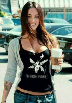 a woman walking down the street while holding a coffee cup in her hand and smiling