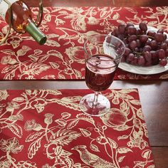 two place mats with wine glasses and grapes on them