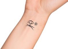 a person's arm with a small tattoo on it that has an umbrella and sun