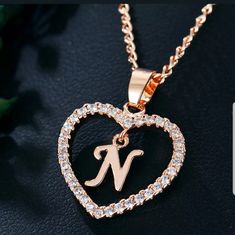 a heart shaped initial necklace with the letter n in it's center surrounded by diamonds