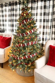 a christmas tree with red, white and black ribbon on it in a living room