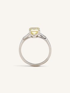 Vintage Art Deco engagement ring centered with a 1.86 carat Fancy Intense Yellow diamond elegantly accented by pair of slender baguette diamonds and a platinum band with sleek lines and a beautifully fine low profile. Fancy Intense Yellow diamonds, also known as "Canary diamonds", are prized for their vibrant, sun-drenched hue. These diamonds are unique due to their intense color saturation, which is a result of the presence of nitrogen molecules that absorb blue light, thus giving the diamond its yellow color. Unlike other diamonds, the value of Fancy Intense Yellow diamonds increases with the richness and purity of their color, rather than their lack of color. Their dazzling yellow hue, combined with the natural brilliance of a diamond, creates a stunning visual impact that is both disti Vintage Art Deco Engagement Ring, Canary Diamond, Yellow Diamond Ring, Yellow Diamonds, Yellow Diamond Rings, Fancy Yellow Diamond, Yellow Rings, Vintage Engagement Ring, Diamond Engagement Rings Vintage