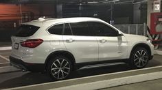 a white bmw suv is parked in a parking lot next to a gas pump at night