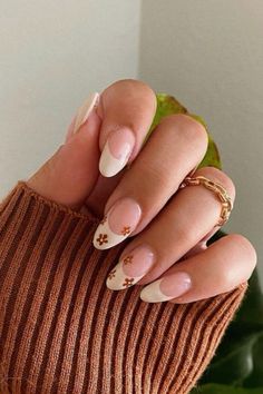 Fall French Tip Nails with Floral Design #fallnails #frenchnails #fallnailsideas #nailidea #falltrends #nailtrends #nails #floraldesign Brown Nails White Flowers, Heart Art Nails, Fall Nail Inspiration Autumn Almond, Short Nail Inspo Autumn, Fall Nail Inspo Almond Short, Dainty Fall Nails, Cute Pink Fall Nails, White Thanksgiving Nails, September Nails Almond