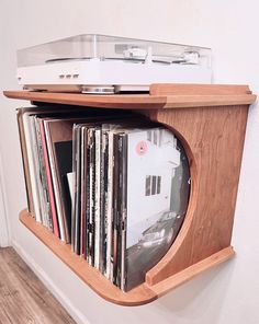 a wooden shelf with cd's and cassettes on the top, in front of a white wall