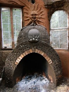 an outdoor brick oven with a sun face on the front and windows behind it,